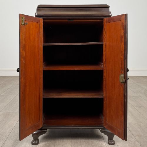 fig 1. An early 20th-century dark mahogany cupboard featuring two panelled doors with small wooden turned knobs, keyhole escutcheon, and cabriole feet.
