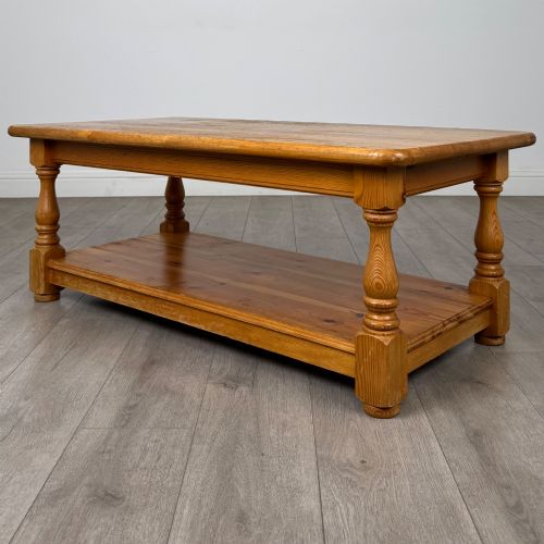 fig 1. A rectangular warm pine coffee table featuring turned legs and a lower full-length storage shelf.