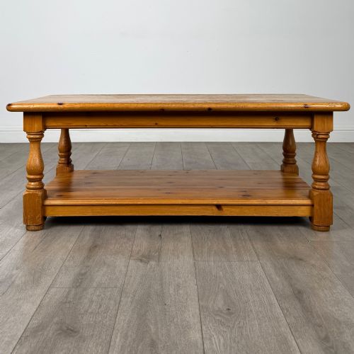 fig 4. A rectangular warm pine coffee table featuring turned legs and a lower full-length storage shelf.