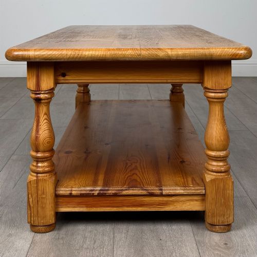 fig 6. A rectangular warm pine coffee table featuring turned legs and a lower full-length storage shelf.