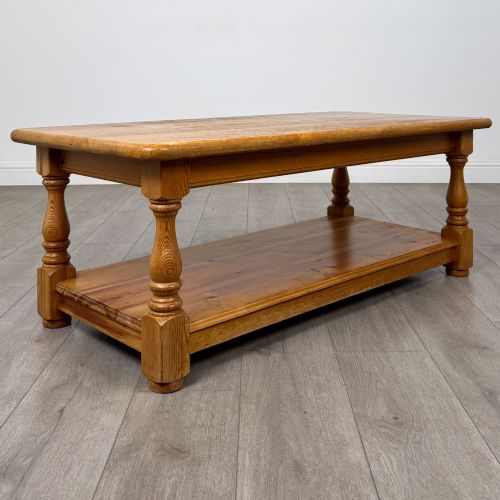 fig 7. A rectangular warm pine coffee table featuring turned legs and a lower full-length storage shelf.