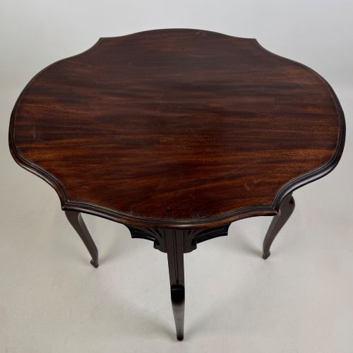 fig 7. An Edwardian dark mahogany side table featuring a shaped top, pierced carved spandrels, slender cabriole legs, and a lower tier shelf.