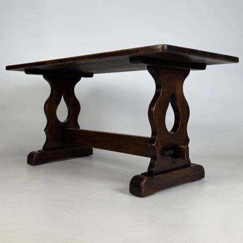 fig 1. A dark oak trestle coffee table featuring shaped side supports with teardrop cut-outs and a low central stretcher.