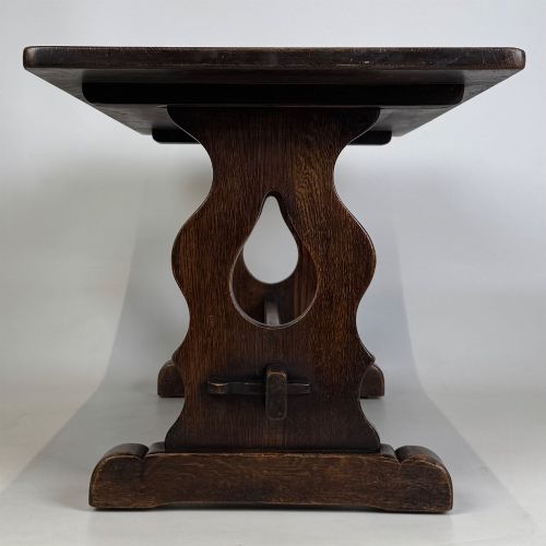 fig 2. A dark oak trestle coffee table featuring shaped side supports with teardrop cut-outs and a low central stretcher.