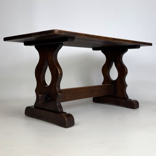 fig 3. A dark oak trestle coffee table featuring shaped side supports with teardrop cut-outs and a low central stretcher.