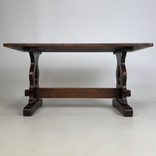 fig 4. A dark oak trestle coffee table featuring shaped side supports with teardrop cut-outs and a low central stretcher.