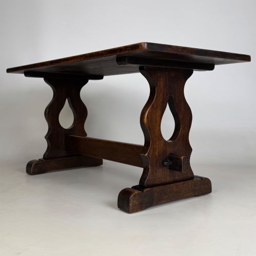 fig 5. A dark oak trestle coffee table featuring shaped side supports with teardrop cut-outs and a low central stretcher.