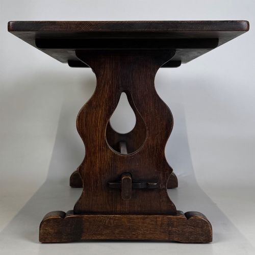 fig 6. A dark oak trestle coffee table featuring shaped side supports with teardrop cut-outs and a low central stretcher.