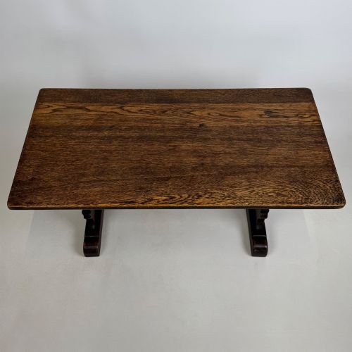 fig 8. A dark oak trestle coffee table featuring shaped side supports with teardrop cut-outs and a low central stretcher.