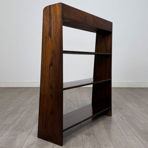 fig 4. A dark oak Edwardian open bookcase with four horizontal shelves holding leather-bound books.