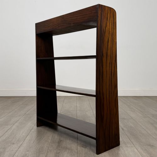 fig 6. A dark oak Edwardian open bookcase with four horizontal shelves holding leather-bound books.