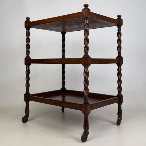 fig 1. A three-tier dark oak tea trolley featuring spiralled barley twist corner supports, turned top finials, and castor wheels.
