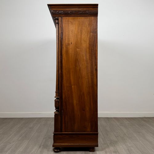 fig 3. A 19th-century French walnut wardrobe with double doors featuring detailed carved foliate panels, central fluted columns, two lower drawers, and a stepped cornice.