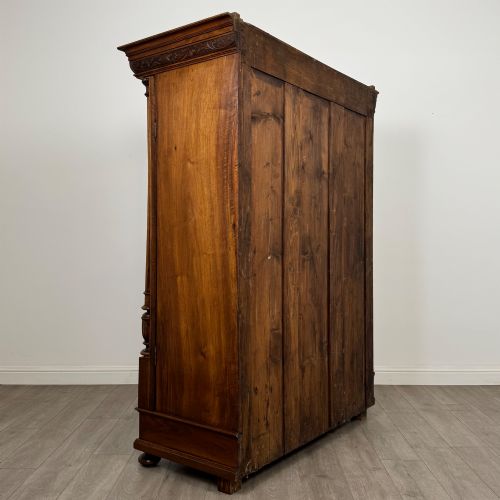 fig 4. A 19th-century French walnut wardrobe with double doors featuring detailed carved foliate panels, central fluted columns, two lower drawers, and a stepped cornice.