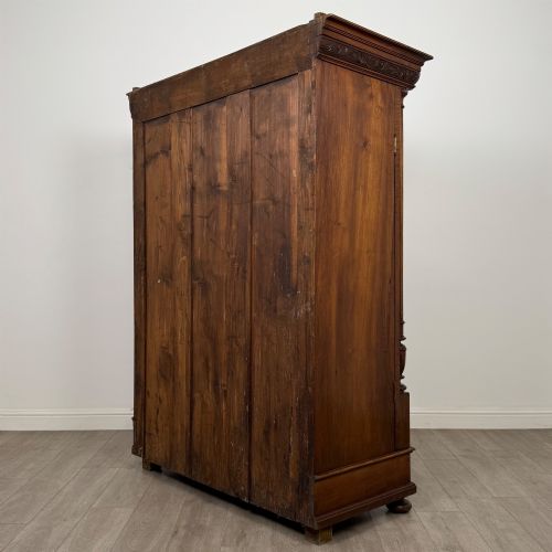 fig 6. A 19th-century French walnut wardrobe with double doors featuring detailed carved foliate panels, central fluted columns, two lower drawers, and a stepped cornice.