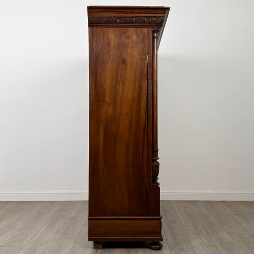 fig 7. A 19th-century French walnut wardrobe with double doors featuring detailed carved foliate panels, central fluted columns, two lower drawers, and a stepped cornice.
