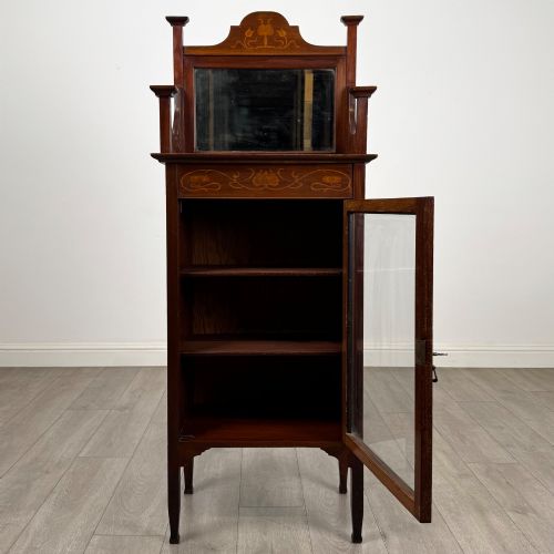 fig 1. An Edwardian mahogany display cabinet featuring a upper mirrored rail with floral wood inlay above a single glazed door cupboard.