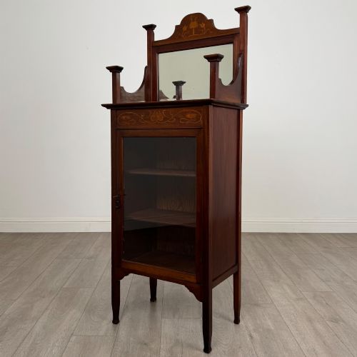 fig 2. An Edwardian mahogany display cabinet featuring a upper mirrored rail with floral wood inlay above a single glazed door cupboard.
