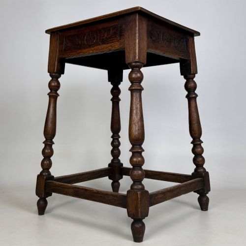 fig 1. An antique dark oak side table featuring carved rosette apron details, turned legs, and lower stretchers.