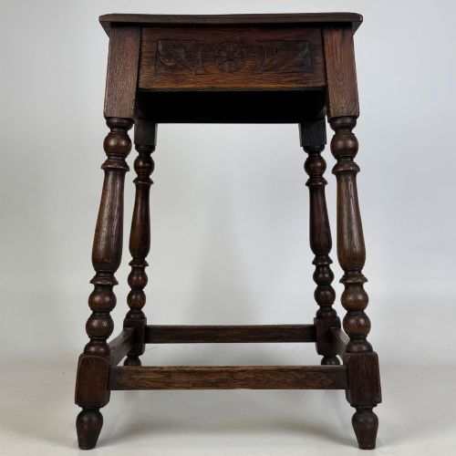 fig 2. An antique dark oak side table featuring carved rosette apron details, turned legs, and lower stretchers.