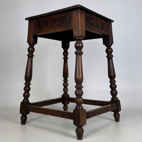 fig 3. An antique dark oak side table featuring carved rosette apron details, turned legs, and lower stretchers.