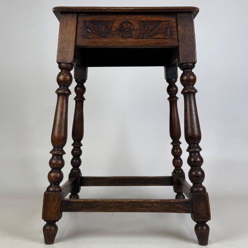 fig 4. An antique dark oak side table featuring carved rosette apron details, turned legs, and lower stretchers.