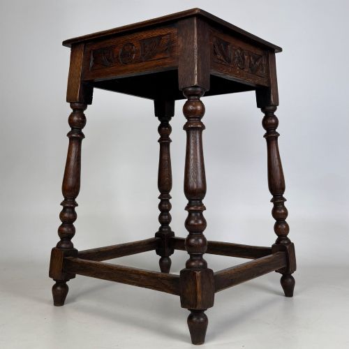 fig 5. An antique dark oak side table featuring carved rosette apron details, turned legs, and lower stretchers.