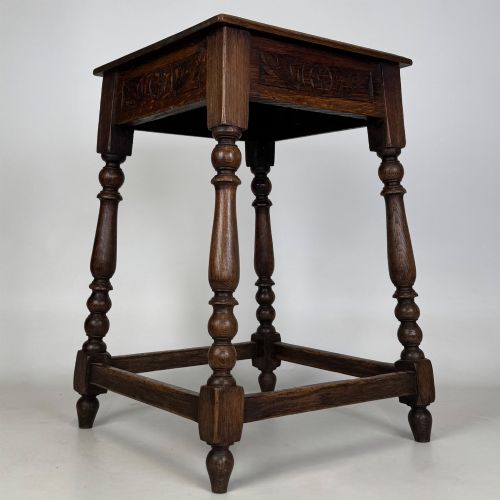 fig 7. An antique dark oak side table featuring carved rosette apron details, turned legs, and lower stretchers.