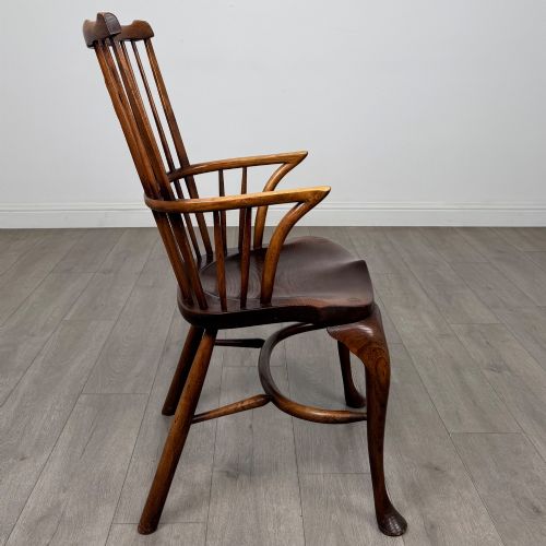 fig 6. A pair of warm brown elm Windsor armchairs featuring shaped top rails, pierced back splats, spindle supports, shaped saddle seats, and front cabriole legs.