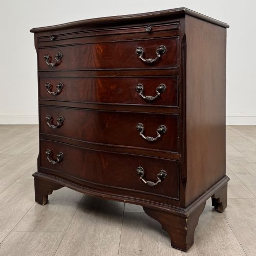 fig 1. A mahogany serpentine-front chest of drawers featuring four graduated drawers with brass handles and bracket feet.