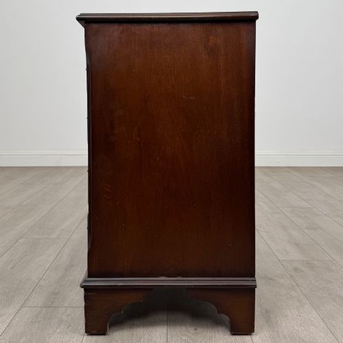 fig 2. A mahogany serpentine-front chest of drawers featuring four graduated drawers with brass handles and bracket feet.