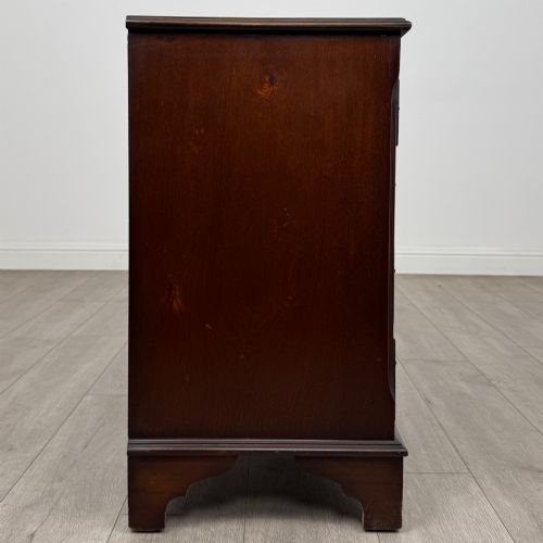 fig 6. A mahogany serpentine-front chest of drawers featuring four graduated drawers with brass handles and bracket feet.