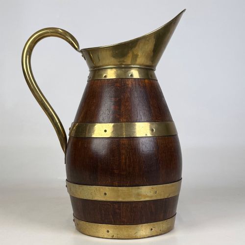 fig 5. A tall dark oak wooden jug styled as an umbrella stand, featuring decorative brass bands, a curved brass handle, and a brass spout.