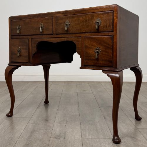 fig 1. An Edwardian mahogany writing table featuring four drawers with ornamental brass drop handles, a central kneehole aperture, and four cabriole legs.
