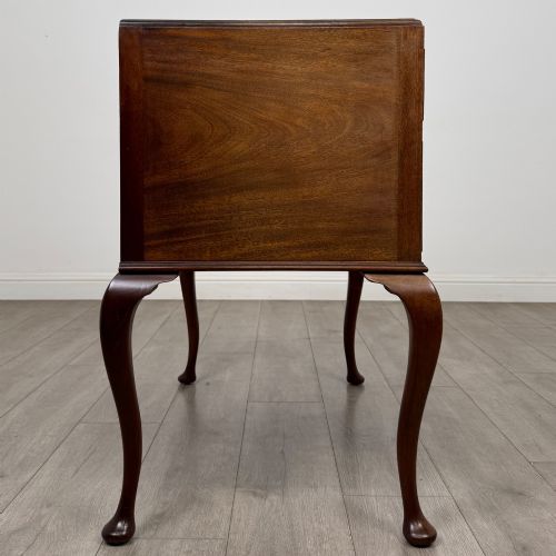 fig 6. An Edwardian mahogany writing table featuring four drawers with ornamental brass drop handles, a central kneehole aperture, and four cabriole legs.