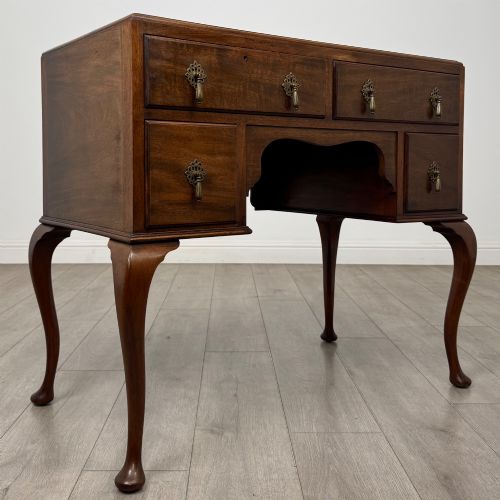 fig 7. An Edwardian mahogany writing table featuring four drawers with ornamental brass drop handles, a central kneehole aperture, and four cabriole legs.