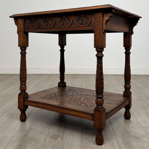 fig 1. An antique Edwardian carved oak side table featuring a carved apron, four turned legs, and a carved foliate motif on its lower shelf.