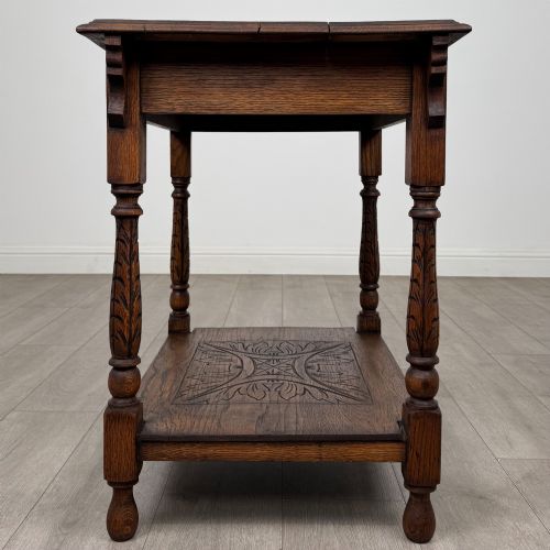 fig 2. An antique Edwardian carved oak side table featuring a carved apron, four turned legs, and a carved foliate motif on its lower shelf.