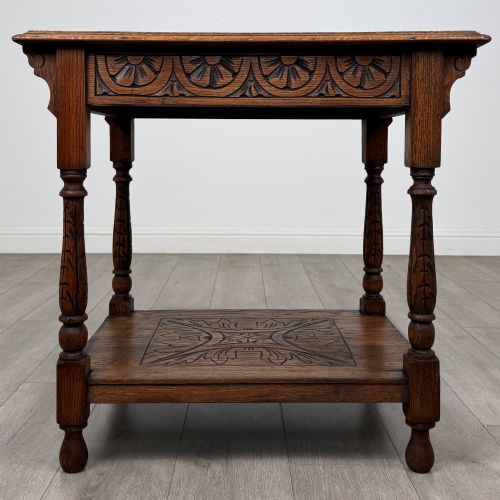 fig 4. An antique Edwardian carved oak side table featuring a carved apron, four turned legs, and a carved foliate motif on its lower shelf.