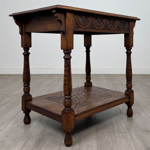 fig 7. An antique Edwardian carved oak side table featuring a carved apron, four turned legs, and a carved foliate motif on its lower shelf.