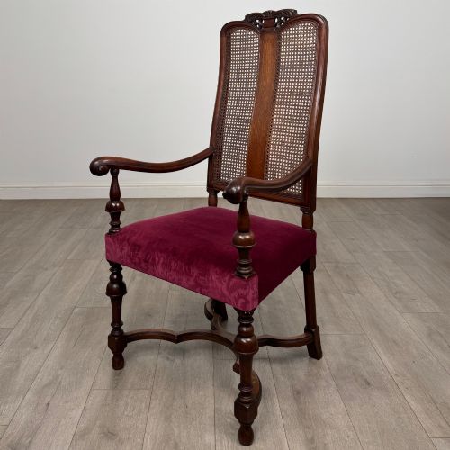 fig 1. A set of mahogany dining chairs featuring high cane-panelled backs, carved top crests, turned legs, and deep red velvet seats.