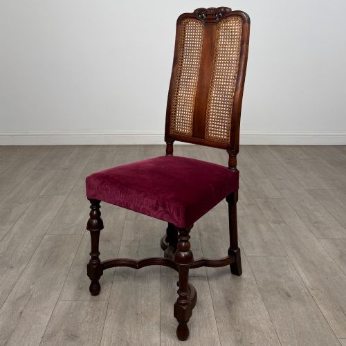 fig 2. A set of mahogany dining chairs featuring high cane-panelled backs, carved top crests, turned legs, and deep red velvet seats.
