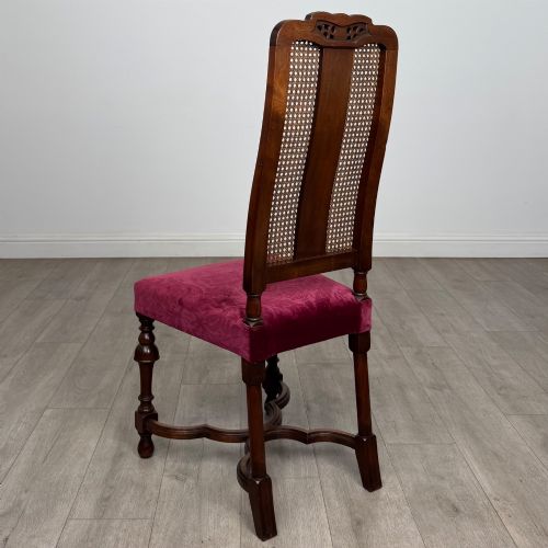 fig 3. A set of mahogany dining chairs featuring high cane-panelled backs, carved top crests, turned legs, and deep red velvet seats.