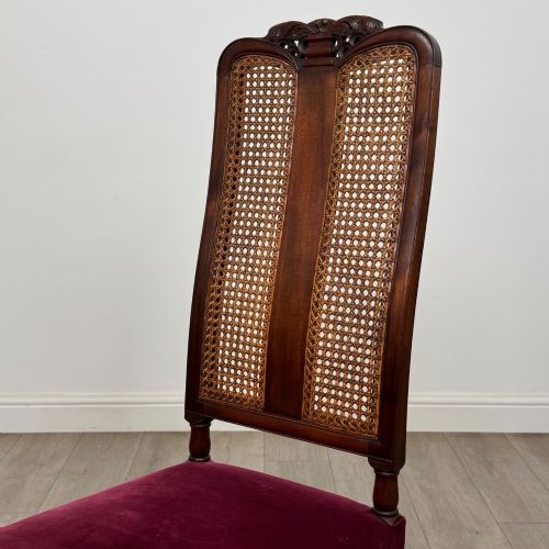 fig 4. A set of mahogany dining chairs featuring high cane-panelled backs, carved top crests, turned legs, and deep red velvet seats.