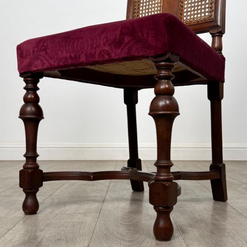 fig 5. A set of mahogany dining chairs featuring high cane-panelled backs, carved top crests, turned legs, and deep red velvet seats.