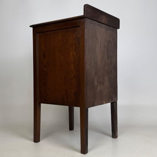 fig 4. An Edwardian dark brown oak cabinet featuring a single panelled door with a round wooden knob supported on four square straight legs.