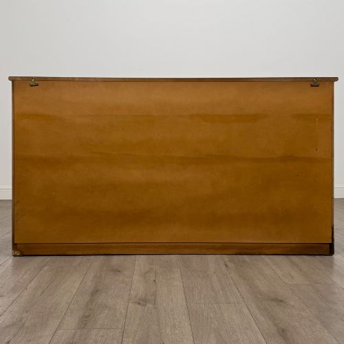 fig 5. A three-door golden oak sideboard featuring three carved drawers, panelled cabinet doors, and metal drop handles.