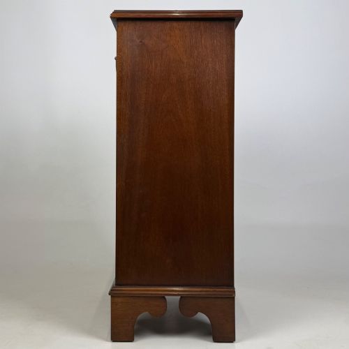 fig 2. A small mahogany open bookcase featuring a single top drawer with brass swan-neck handles, satinwood inlay, open lower shelving, and shaped bracket feet.