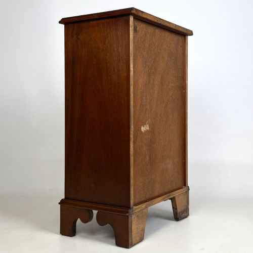 fig 3. A small mahogany open bookcase featuring a single top drawer with brass swan-neck handles, satinwood inlay, open lower shelving, and shaped bracket feet.
