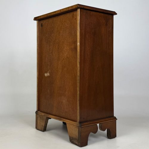 fig 5. A small mahogany open bookcase featuring a single top drawer with brass swan-neck handles, satinwood inlay, open lower shelving, and shaped bracket feet.